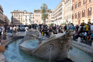 Lively scene in front of the Barcaccia Fountain in Rome.