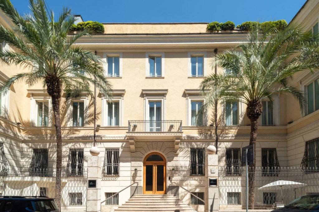 View of the Hotel Capo d´África – Colosseo from the outside, with two palm trees in front.