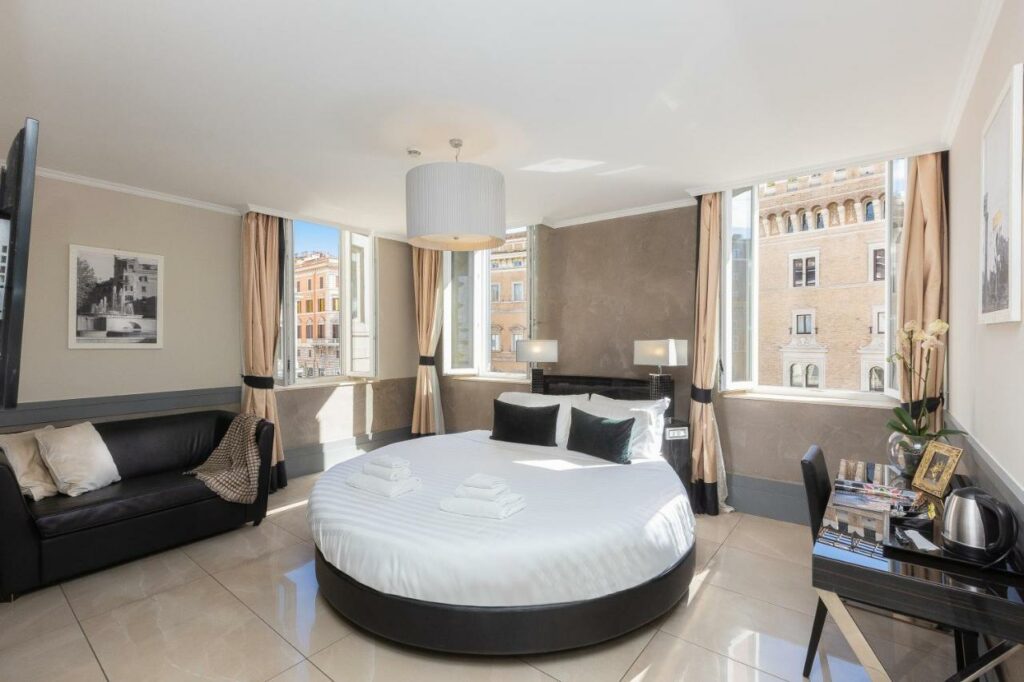 A beautifully lit hotel room with a round queen-size bed and a sofa.