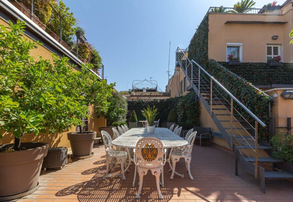 Big table with chairs on the terrace of the Harry's Bar Trevi Hotel & Restaurant, potted plants