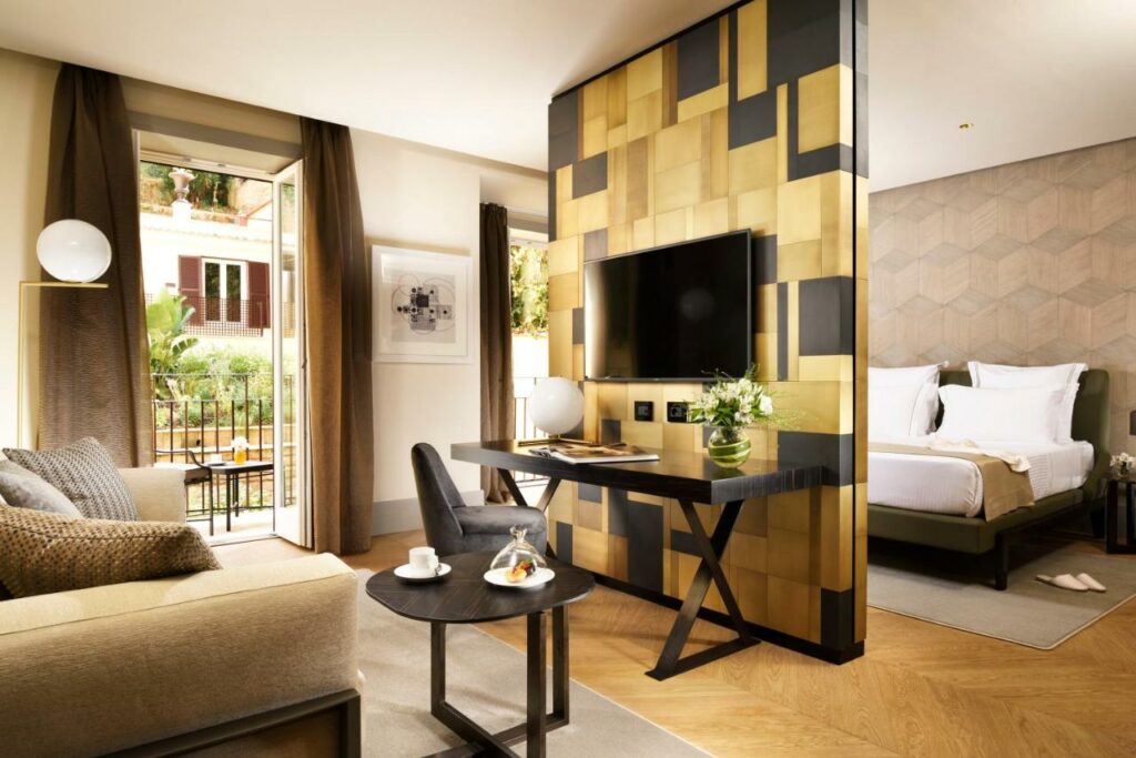 A cozy hotel room featuring a comfortable bed, sofa bed, a sleek desk, and a modern television.