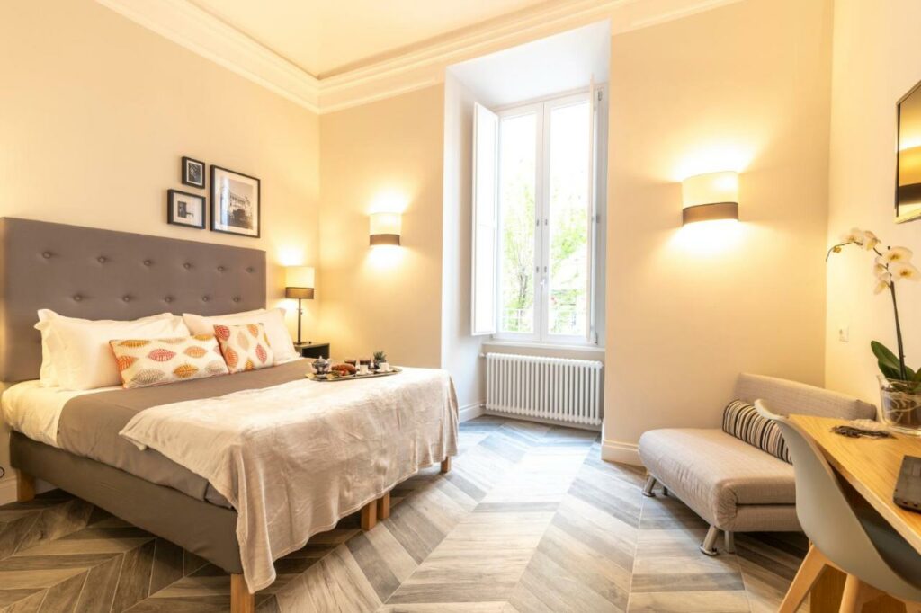 Bright, modern hotel room with a queen-size bed and a sofa.