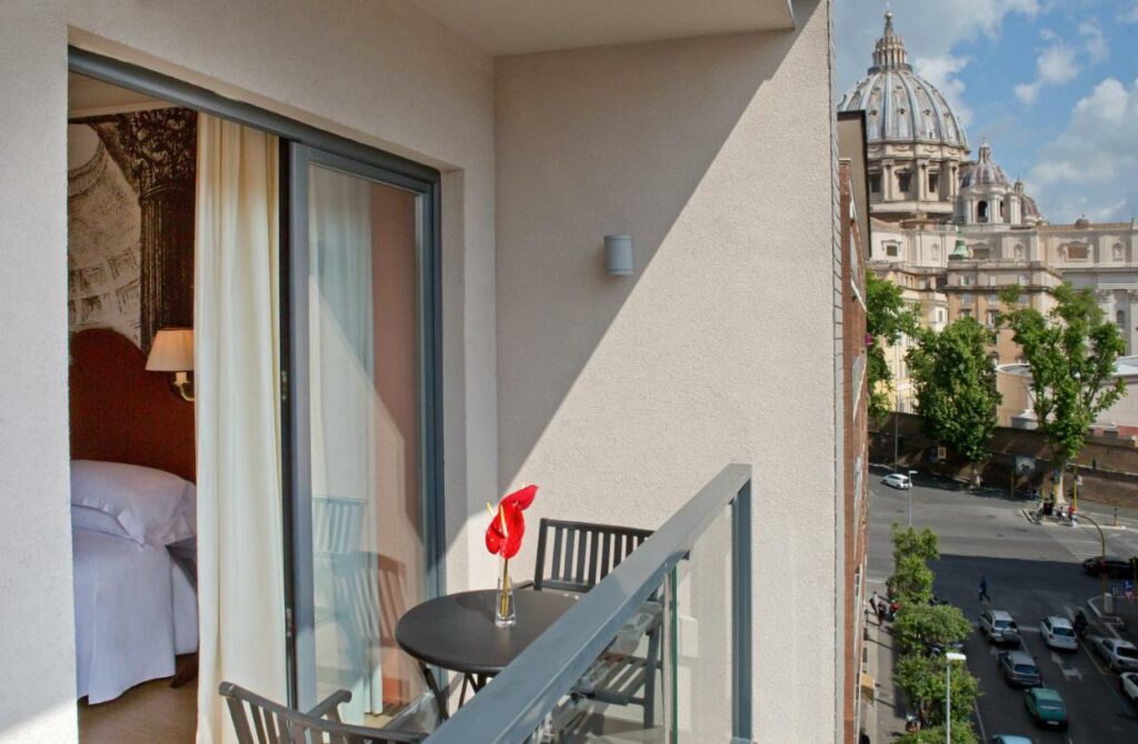 Balcony overlooking cathedral with bed and table.